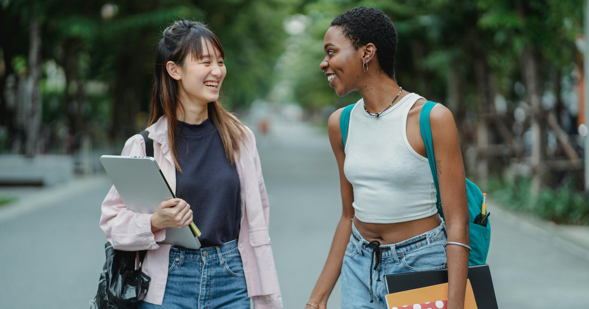 Two young women of different races engaged in conversation while walking, illustrating the significance of meaningful interactions.