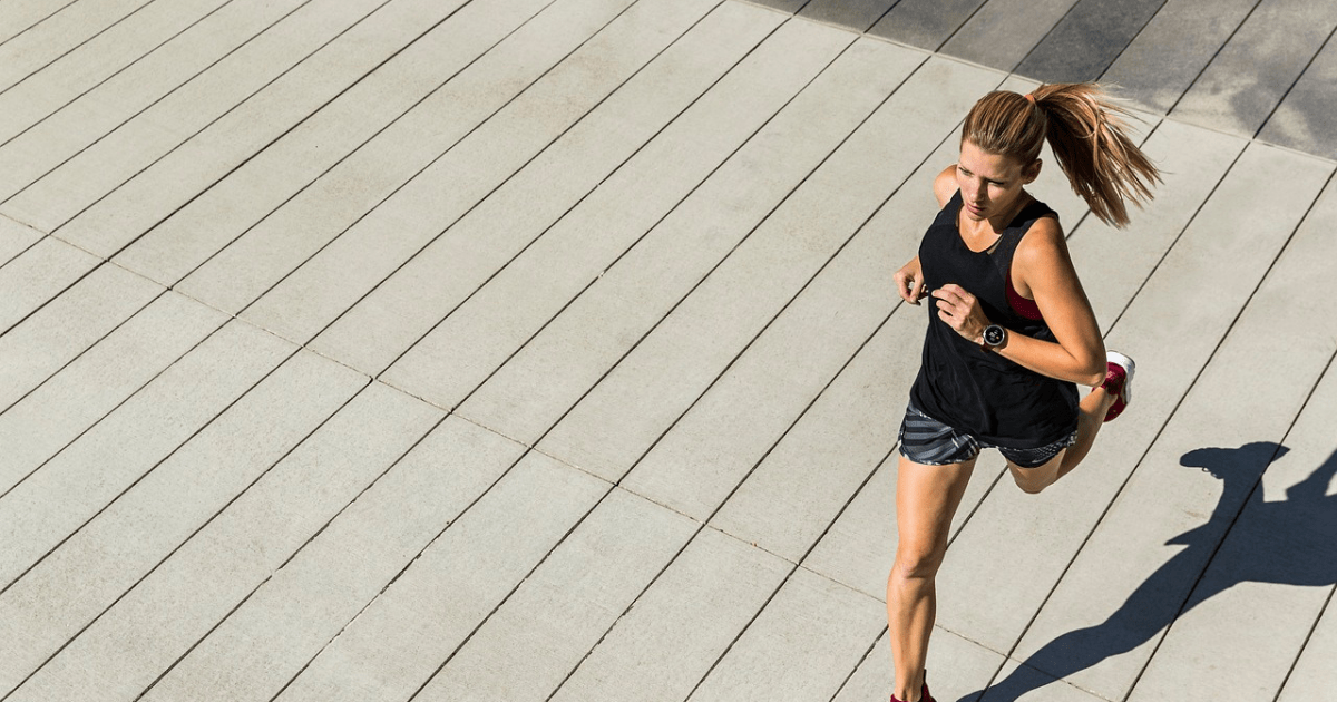 A sporty woman running outdoors, embodying active wellness and physical health.