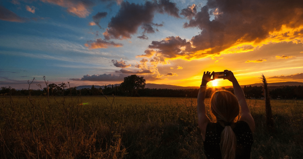 Capturing the Beauty of Nature: A Woman Snaps the Sunset, Symbolizing the Positivity Nature Brings