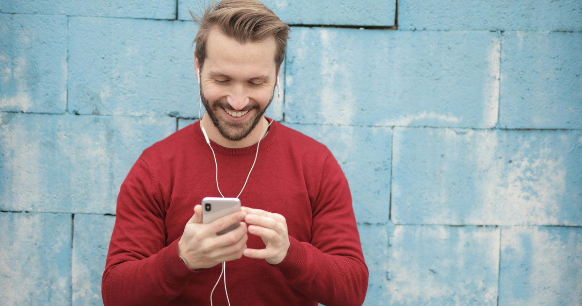 A man wearing headphones, joyfully listening to music on his mobile phone, symbolizing inner strength and embracing change through music.