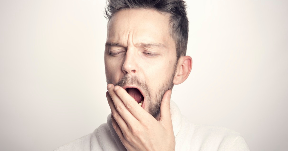 A man yawns and looks tired, indicating the effects of sleep deprivation.