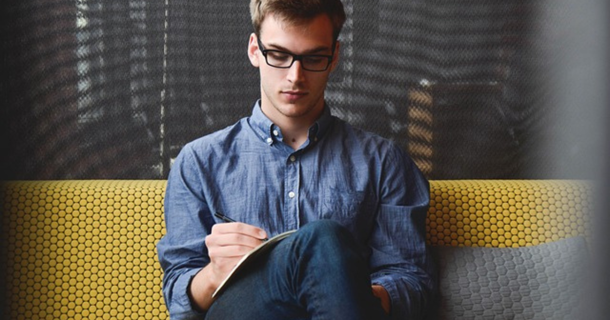 Focused man writing intently, displaying determination to overcome procrastination.