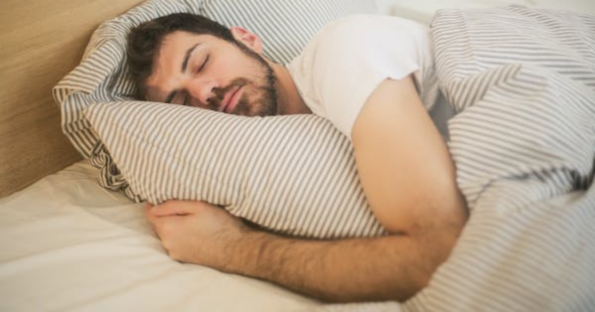 A man sleeps deeply in a cozy bed, highlighting the importance of a good bedroom environment for quality sleep.