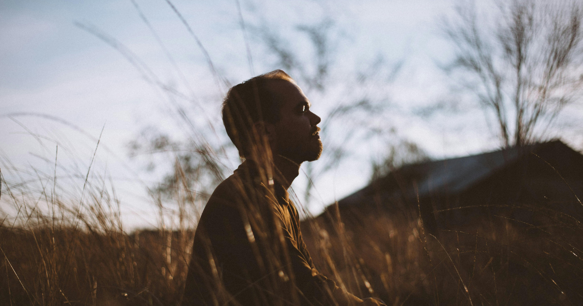 A man meditating and contemplating his existence in the dusky evening at an abandoned location.