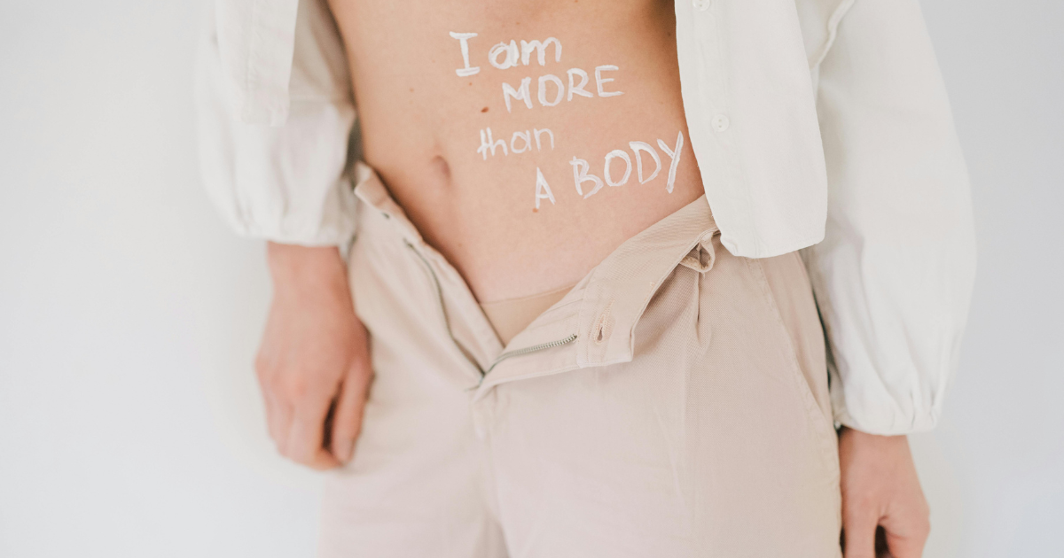 An image of a belly with the words 'I'm more than a body,' symbolizing that the human soul transcends physical appearance and gender identity.