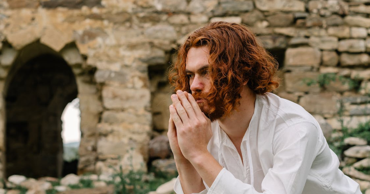 An image of a man sitting in a secluded area, with his hands resting on his chin, deep in contemplation and manifestation.