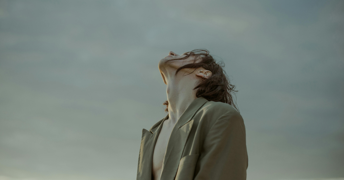 Image: A person meditating with closed eyes, their face turned upwards towards the sky, as if manifesting their dreams while calling upon the universe.