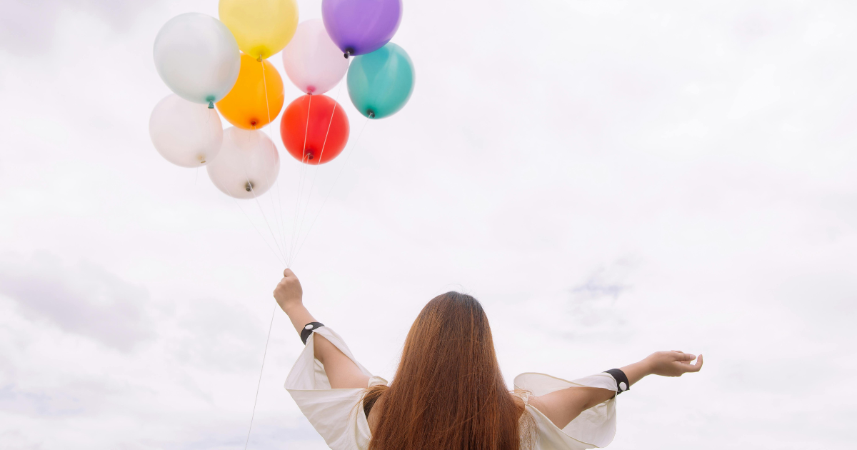 Image: A woman releasing balloons into the sky, symbolizing the art of letting go and tranquility.