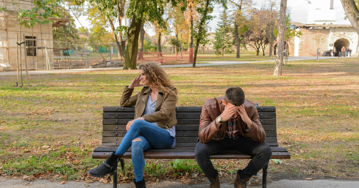 A photograph of a couple facing away from each other, indicating the gesture of letting go in a relationship as they turn in opposite directions.