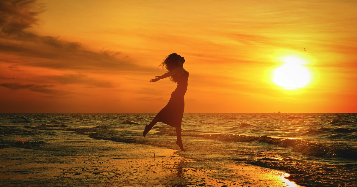 The Art of Letting Go: A silhouette of a woman jumping joyfully into the ocean at sunset, symbolizing the freedom and liberation found in the art of letting go.