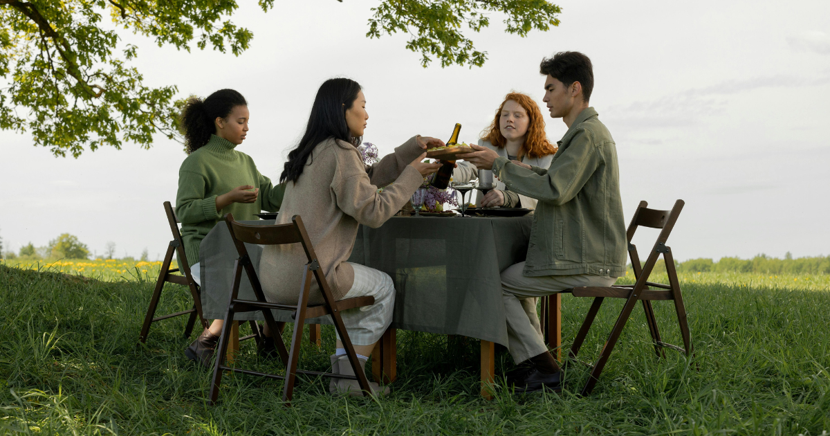 Friends gathered around a meal in a serene natural setting, highlighting the importance of socializing and support networks in coping with the aftermath of divorce.