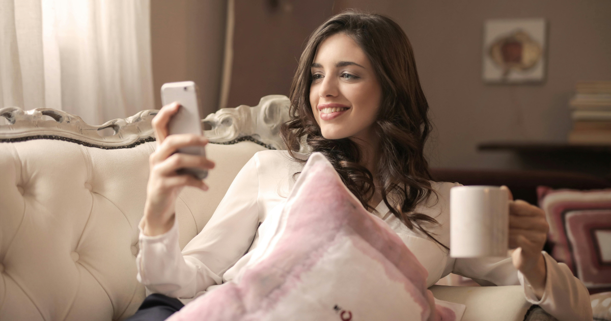 The woman's happiness as she watches positive videos on her phone, smiling brightly, illustrates how engaging with uplifting content can help distract from a difficult past.