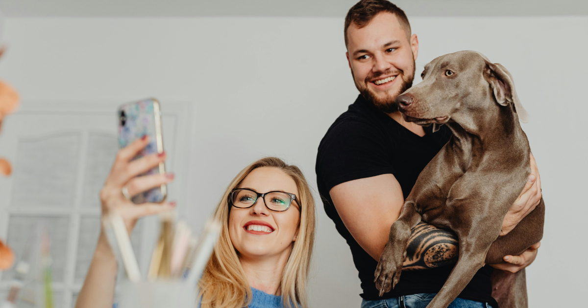 Image: A couple taking a selfie with their pet dog, showing the cherishment of a childfree life.