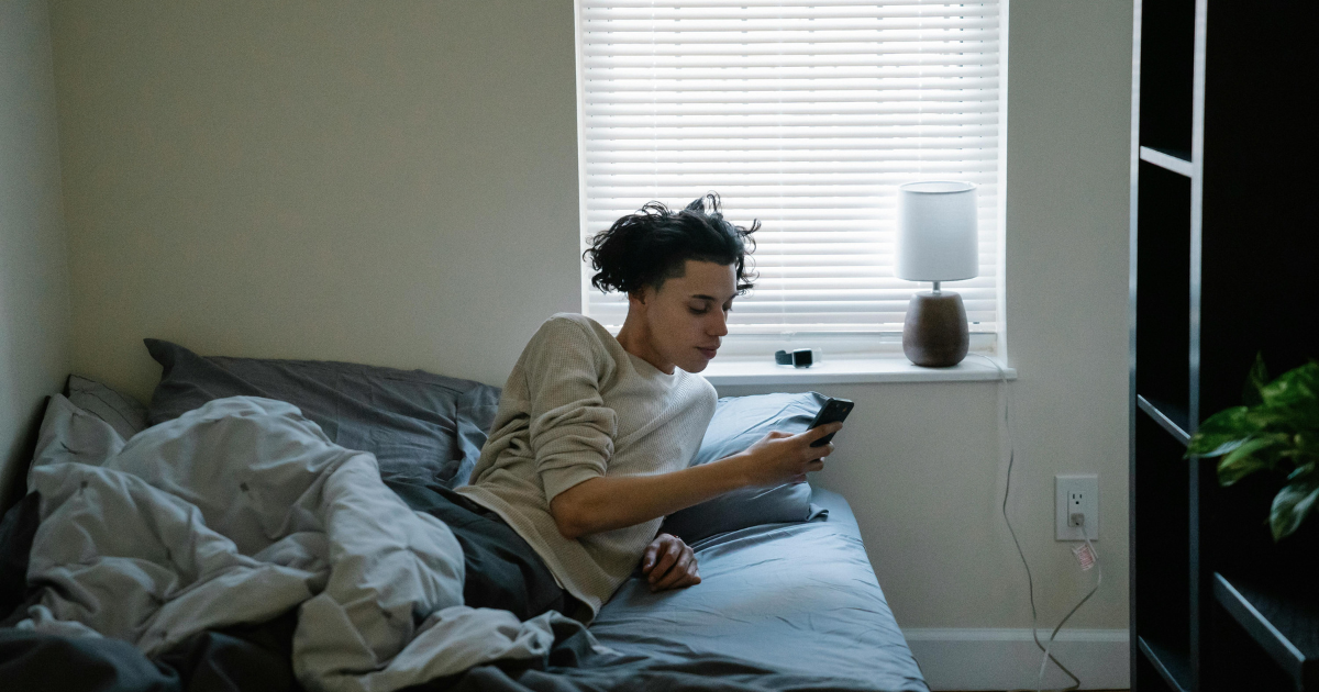 Man engrossed in his phone while lying in bed