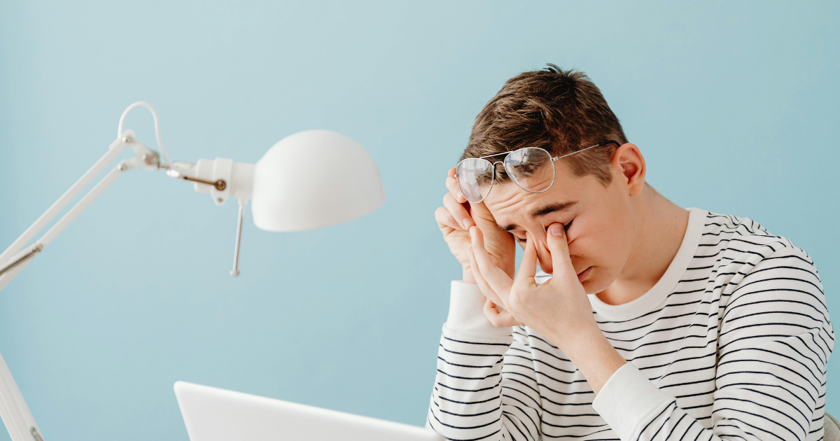 Image: Man rubbing his eyes at office desk due to fatigue from bed rotting.