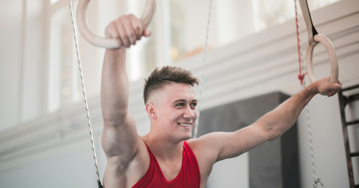 A man smiling while exercising in a gym, showing the effect of self-love
