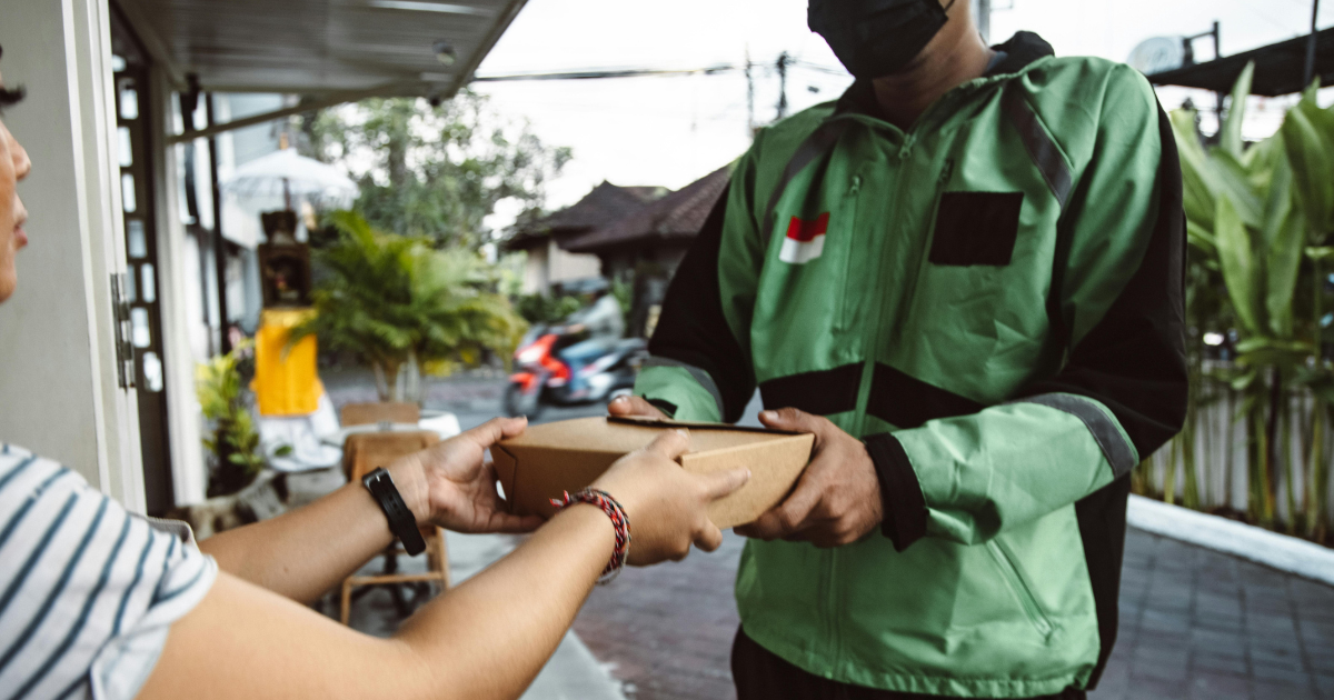 A woman smiling as she gives something to a stranger.