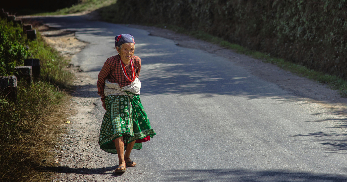 Elderly Woman Walking Alone by the Road