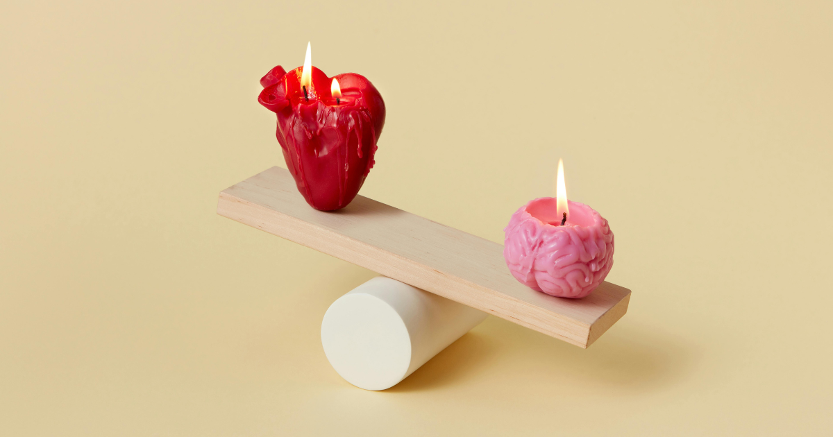 A heart-shaped candle and a brain-shaped candle burning on a seesaw, symbolizing the balance between emotions and rational thinking in the context of the Platonic mind.