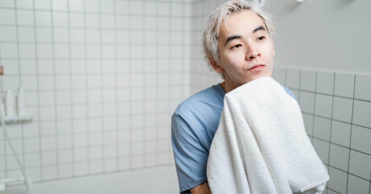 "Man pat drying his face after wash, showing the importance of cleansing in looking good without makeup