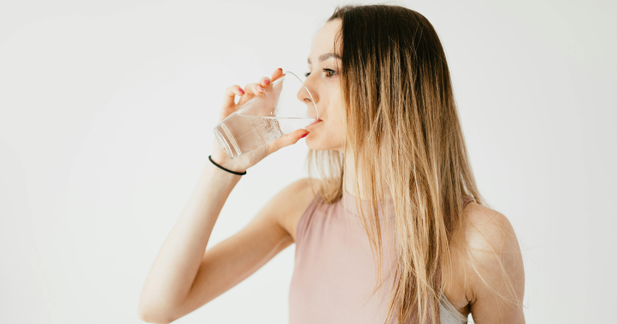 **Image Alt Text:** Woman drinking water shows the importance of hydration to look good without makeup.