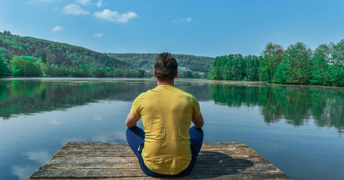 A man meditating amidst serene nature, illustrating the power of silence.