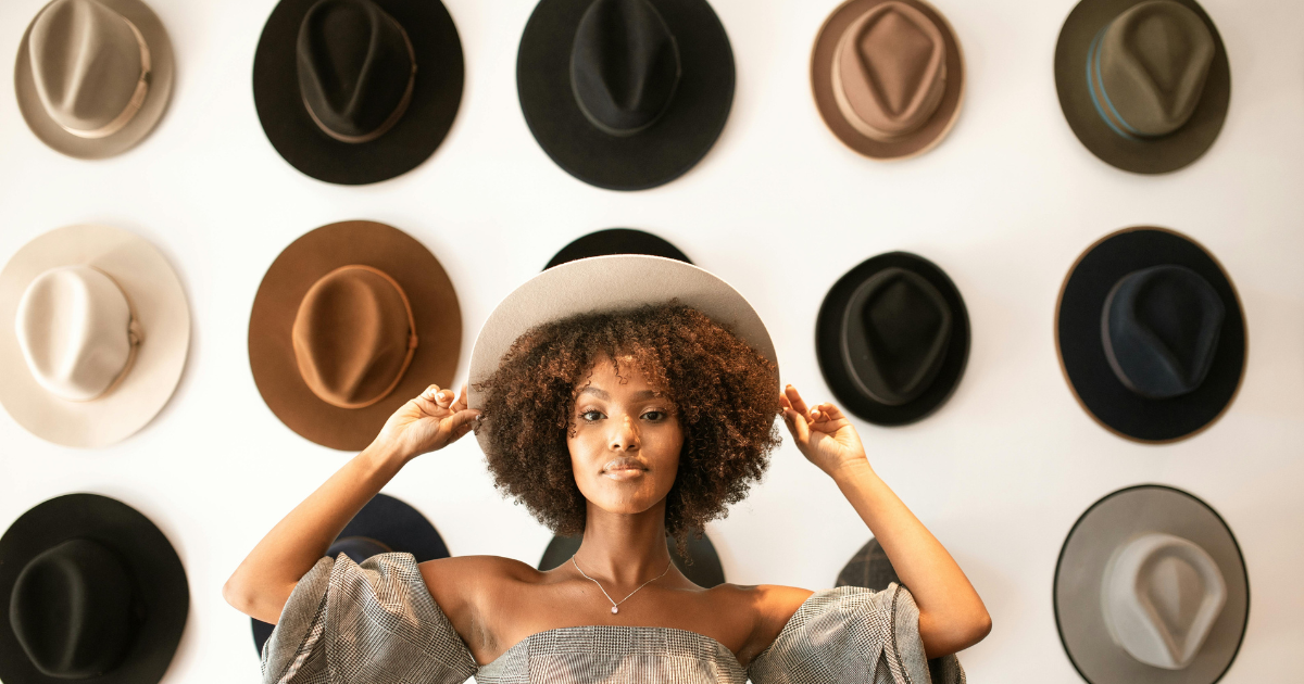 A model wearing a brimmed hat with multiple hats in the background, highlighting the importance of brimmed hats in summer fashion.