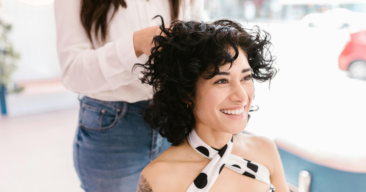 A beautiful woman in a happy mood getting a hairstyle from a friend.