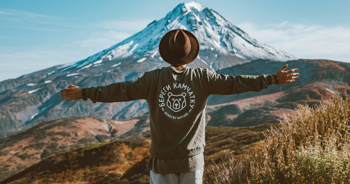 Image of a man celebrating freedom with open arms in the lap of a mountain.